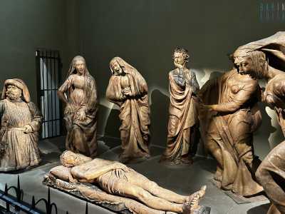 Al centro giace il corpo di Cristo, disteso con il capo reclinato su un cuscino. Attorno a lui, sei personaggi immersi nel dolore partecipano al lutto con gesti e posture differenti, ognuno espressione di un sentimento unico di disperazione